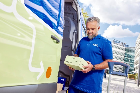 GLS-driver-looking-at-a-parcel-infront-of-a-van