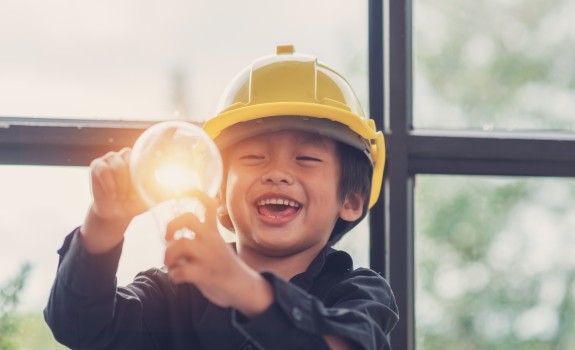 Enfant souriant qui tient une ampoule