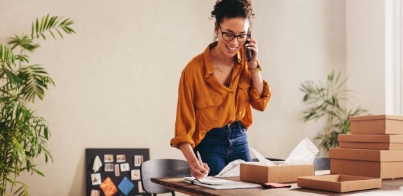 Vrouw die aan de telefoon praat met GLS-pakketten naast haar
