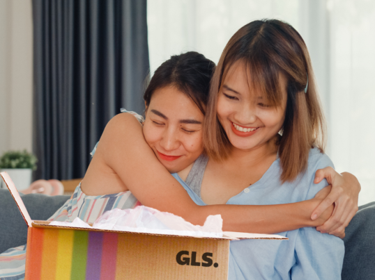 Two women hugging while hopening a GLS parcel.