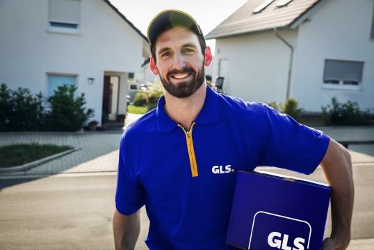 GLS delivery driver with a parcel on a street