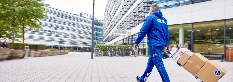 GLS:n työntekijä jakaa kärryillä paketteja kadulla.