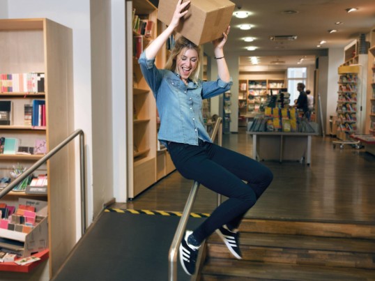 Customer slides down the banister with a parcel in a ParcelShop 