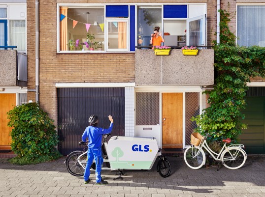 GLS delivery driver delivers parcels to warehouse worker